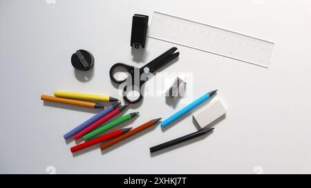 Photo of office equipment. Scattered randomly on a white background. Colored pencils, scissors, stapler, eraser, pencil sharpeners, rules. Colored pen Stock Photo