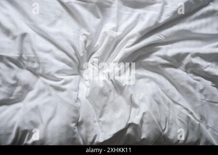Crumpled and wrinkled white bed sheet, top view as background Stock Photo