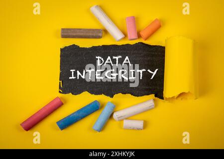 Data integrity. Text under torn yellow paper on a blackboard. Stock Photo