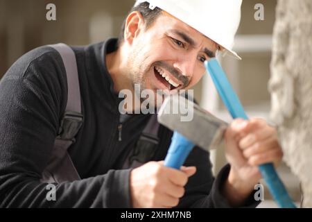 Construction worker suffering accident hiting hand with hammer working in a house Stock Photo