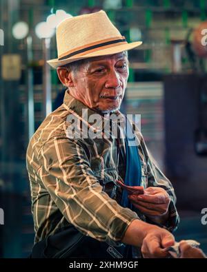 Senior Man Wearing a Straw Hat in a Busy Market Stock Photo