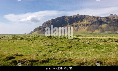 South Iceland mountain landscape along Route 1 on sunny day with green grasslands and rocky mountains in the background. Stock Photo