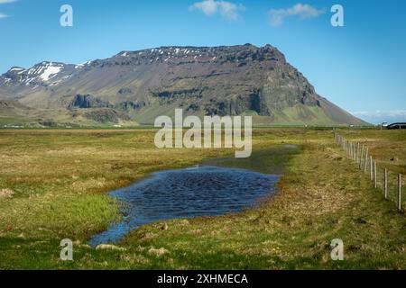 South Iceland Eyjafjoll mountain range landscape on sunny day with green grasslands, swamps and rocky mountains in the background. Stock Photo