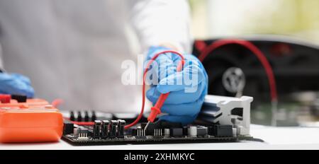 Close-up of technician measuring voltage of in computer mainboard using electronic digital multimeter. Computer hardware, repairing and upgrade Stock Photo