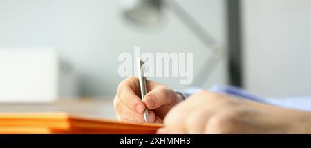 Close-up of male hand writing personal address on yellow envelope. Signing envelopes and correspondence processing. Delivery service concept Stock Photo