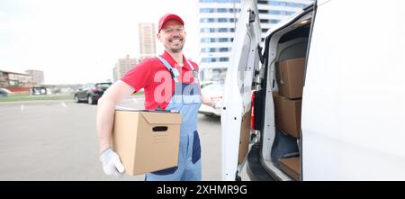 Smiling courier with parcels near delivery van Stock Photo