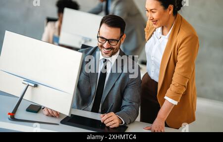 Senior business manager talking with experienced colleague while using computer in office. Stock Photo