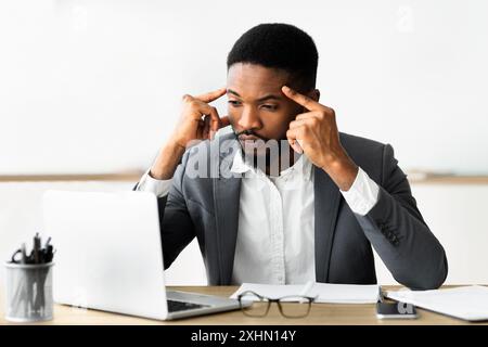 Concentrated african employee analyzing information on laptop, working in office Stock Photo