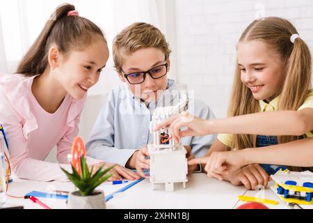 Three Children Collaborating on Robotics Project in a Classroom Setting Stock Photo