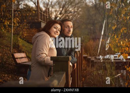 happy married couple over 50 years old walking along the embankment in the park on a warm sunny evening in autumn, hugging. happy family life concept Stock Photo
