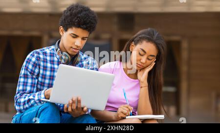 Teen Guy Using Laptop While Teen Girl Takes Notes Outside Stock Photo