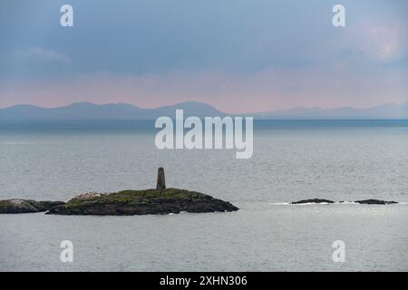 Rhoscolyn beacon off the coast of Anglesey with the mountains of the mainland on the horizon. Stock Photo