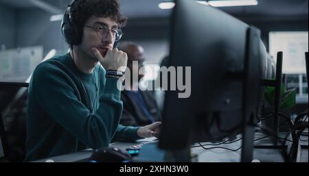 Portrait of a Thoughtful Engineer Working on Desktop Computer in a Technological Office Environment. Research and Development Department Writing Software Code for an Advanced Neural Network Project Stock Photo
