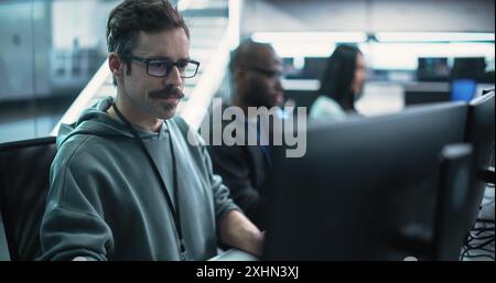Portrait of a Thoughtful Engineer Working on Desktop Computer in a Technological Office Environment. Research and Development Department Writing Software Code for an Advanced Neural Network Project Stock Photo