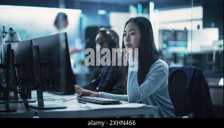 Portrait of a Thoughtful Asian Engineer Working on Computer in a Technological Corporate Laboratory. Young Woman Writing Software Code for an Innovative Internet and Software as a Service Project Stock Photo