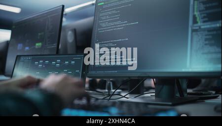 Close Up of a Software Developer Working on a Desktop Computer, Programming Code Running on Display. Specialist Typing on Keyboard, Coding and Implementing a Technical Feature Stock Photo