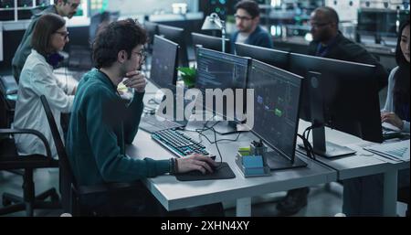 Team of Talented Young Professionals Working in a Technological Research and Development Facility. Diverse Specialists Using Computers, Writing Code, Planning Innovative Information Technology Project Stock Photo