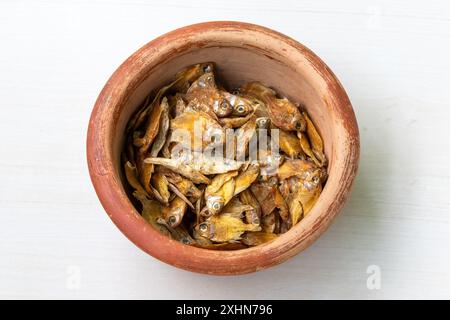 Dried rupchanda shutki or chinese pomfret fish in earthen pot on light white wooden background. Stock Photo