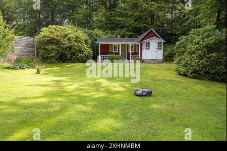 A robotic lawnmower mows the grass on a house plot in Skåne, Sweden Stock Photo