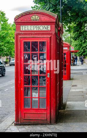 Traditional red British telephone boxes on the pavement on Elgin Avenue in London, UK Stock Photo