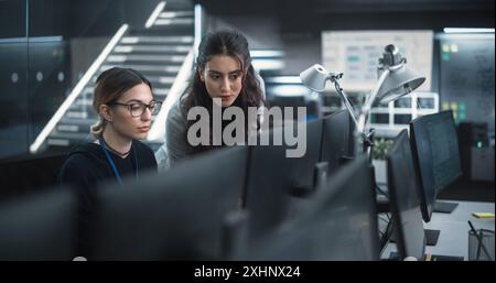 Young Female Software Developer Working on Computer Together with a Friendly Colleagues. Female Asking Advice from a Manager About a Solution for Their Collaborative Tech Project Stock Photo