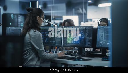 Engaged Young Engineer Working on Computer in a Technological Office Environment. Beautiful Multiethnic Woman Writing Software Code for a Blockchain Project. Photo from the Back Stock Photo