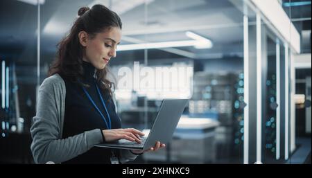 Portrait of a Beautiful Happy Female Using Laptop Computer, Looking Around the Office, Thinking and Solving Problems. Information Technology Specialist, Software Engineer or Developer Stock Photo
