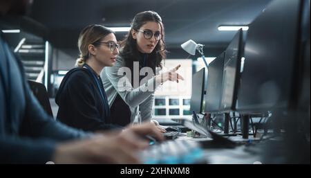 Two Beautiful Women Working in a Cyber Security Software Development Department. Young Manager Updating Software Developer on the Artificial Intelligence Safety Project Stock Photo