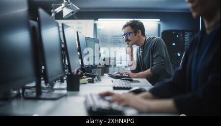 Portrait of a Thoughtful Engineer Working on Desktop Computer in a Technological Office Environment. Research and Development Department Writing Software Code for an Innovative Internet Project Stock Photo
