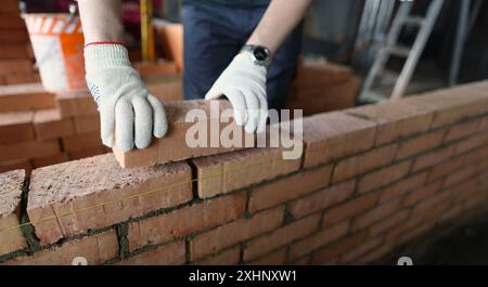 Male builder hands making make brickwork using red bricks Stock Photo