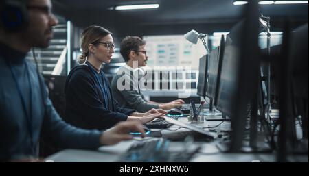 Focused Young Multiethnic Female Software Developer Working on Computer Together with Two Creative Male Colleagues. Data Protection Center with Servers, Storage Hardware and eBusiness Research Stock Photo