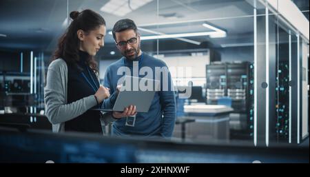 Portrait of Two Female and Male Engineers Using Laptop Computer to Analyze and Discuss How to Proceed with the Artificial Intelligence Software. Casually Chatting in High Tech Research Office Stock Photo