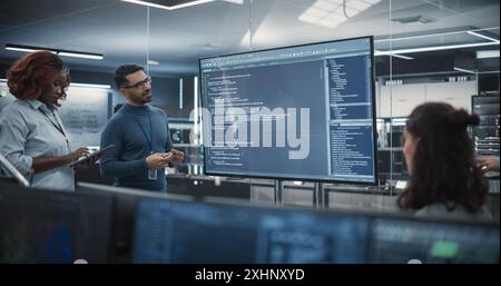 Group of Multiethnic Software Developers Having a Meeting in Order to Review the Code Done by Computer Engineering Department. Specialists Brainstorming New Ideas and Solving Problems in the Office Stock Photo