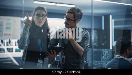 Multicultural Chief Technology Officer Talking to Software Developer, Discussing Neural Network Updates in High Tech Research and Development Facility. Professional Computer Specialists at Work Stock Photo