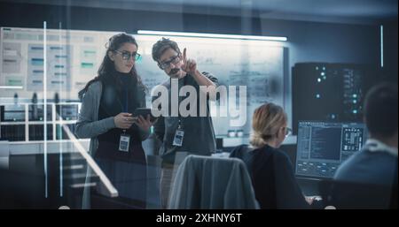 Multicultural Chief Technology Officer Talking to Software Developer, Discussing Neural Network Updates in High Tech Research and Development Facility. Professional Computer Specialists at Work Stock Photo