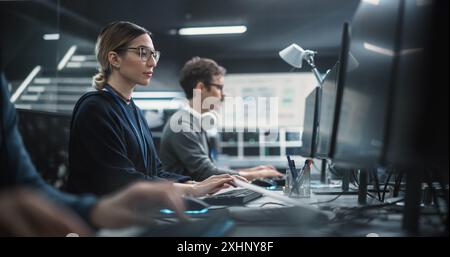 Portrait of a Thoughtful Young Engineer Working on Computer in a Technological Office Environment. Young Multiethnic Woman in Glasses Writing Software Code for an Innovative Internet Project Stock Photo