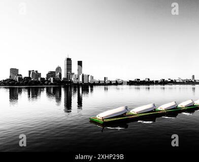 View across the Charles River of Boston's Back Bay skyline in black and white with a smalll boat pier in color in the foreground. Stock Photo