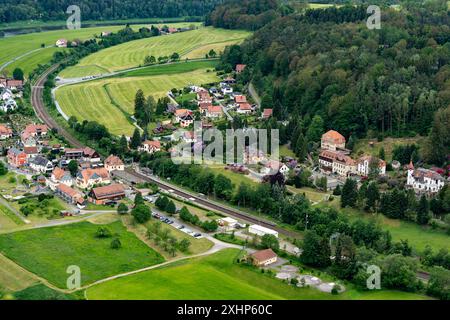 A small town with a train track running through it. The train is not in use. The town is surrounded by a large green field Stock Photo