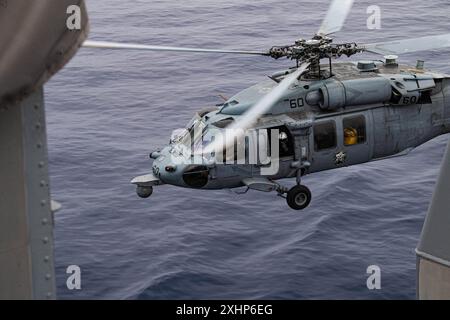 An MH-60S Sea Hawk helicopter from the “Blackjacks” of Helicopter Maritime Strike Squadron (HSC) 21 preforms routine survalience operations around the Stock Photo