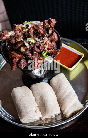 Shekla Tibs is a savory Ethiopian national meal of sauted meat and spices, traditionally served in a clay pot with injera Stock Photo