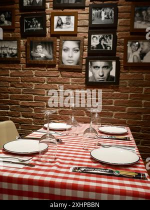 Italian restaurant interior with check tablecloth and iconic Italian images on the wall. Stock Photo