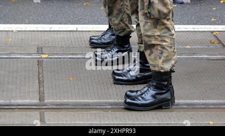 Anonymous unrecognizable generic infantry army soldiers standing at attention in a row on the street, legs boots closeup detail shot, copy space, gree Stock Photo