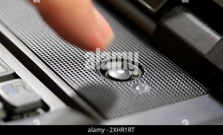 Man's finger about to press the laptop computer power button, hovering over the power on key about to boot, start or restart the device, one person, o Stock Photo