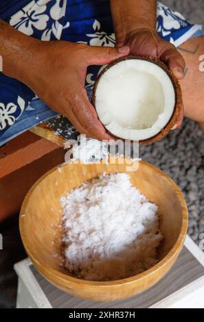 French Polynesia, Tahiti island, Polynesian grating a coconut in a wooden bowl Stock Photo