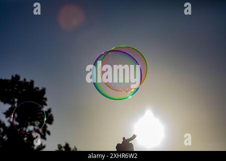 Pretty, ethereal rainbow coloured soap bubbles floating serenely in a sunlit sky Stock Photo