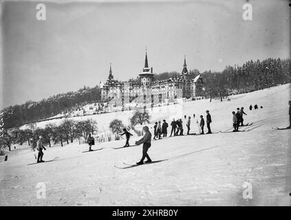 Exterior view of the Grand Hotel Dolder in a winter landscape, view from a distance. In the foreground skiers on the slopes in the Swiss Alps. Vintage Swiss Historical Mountaineering Photography,  1910, Photo Credit: Unknown Stock Photo