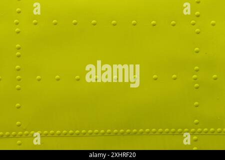 Abstract background made of sheet metal with rivets, yellow background. Stock Photo