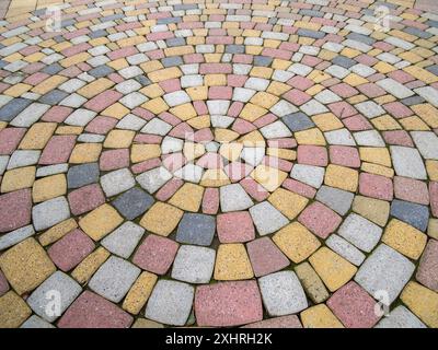 Laying multi-colored paving stones in concentric circles Stock Photo