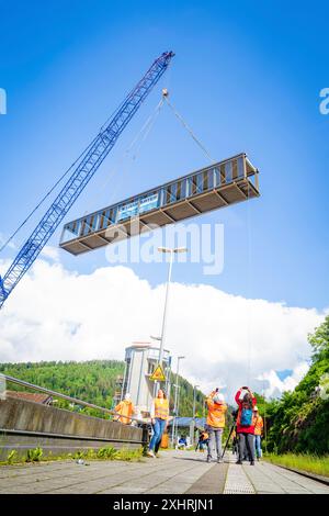 Workers in protective clothing watch a crane lifting a bridge in sunny weather with blue sky and white clouds, bridge lifting Hermann Hesse railway Stock Photo