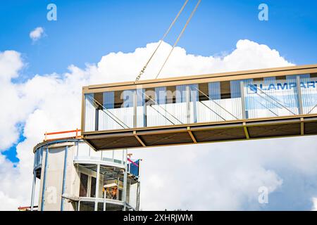 Close-up of a bridge being lifted by a crane and a building in the background with blue sky and white clouds, bridge lifting Hermann Hesse railway Stock Photo